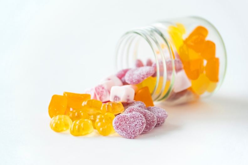 Supplement gummies spilling from a glass jar