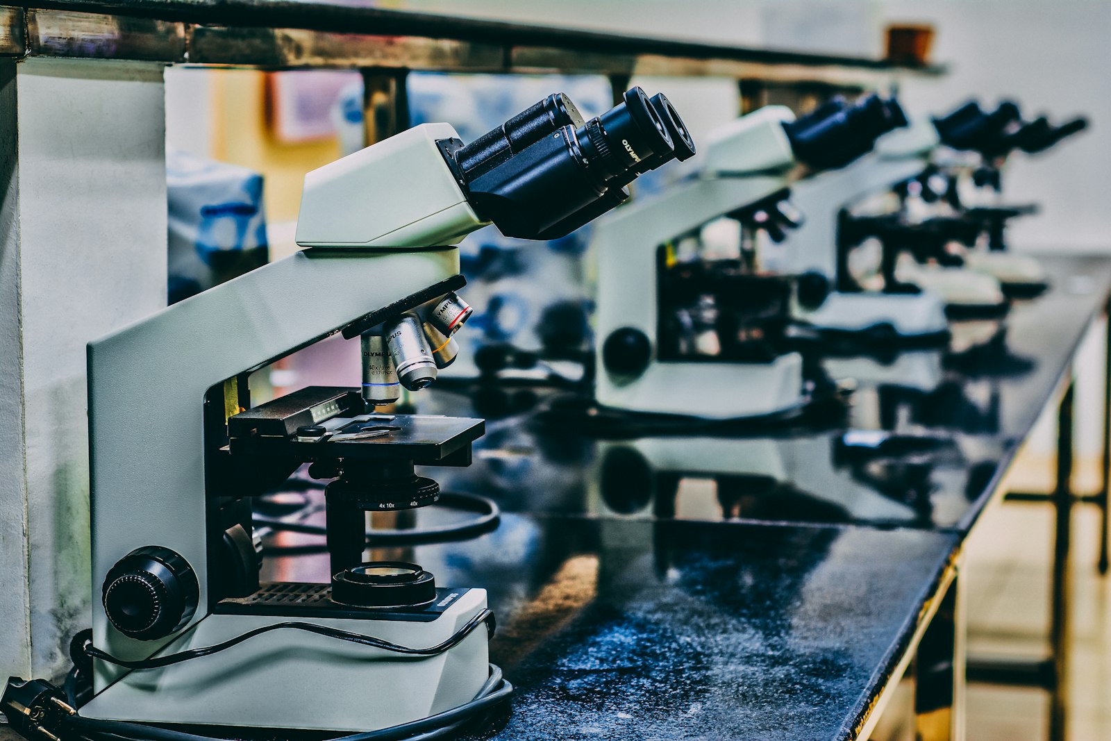 Row of laboratory microscopes on a dark bench